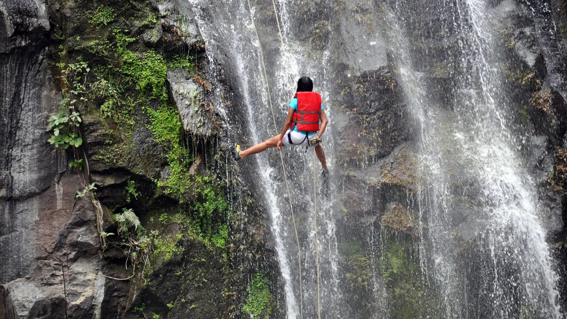 A canyoner rappelling down a waterfall on a guided canyoning descent
