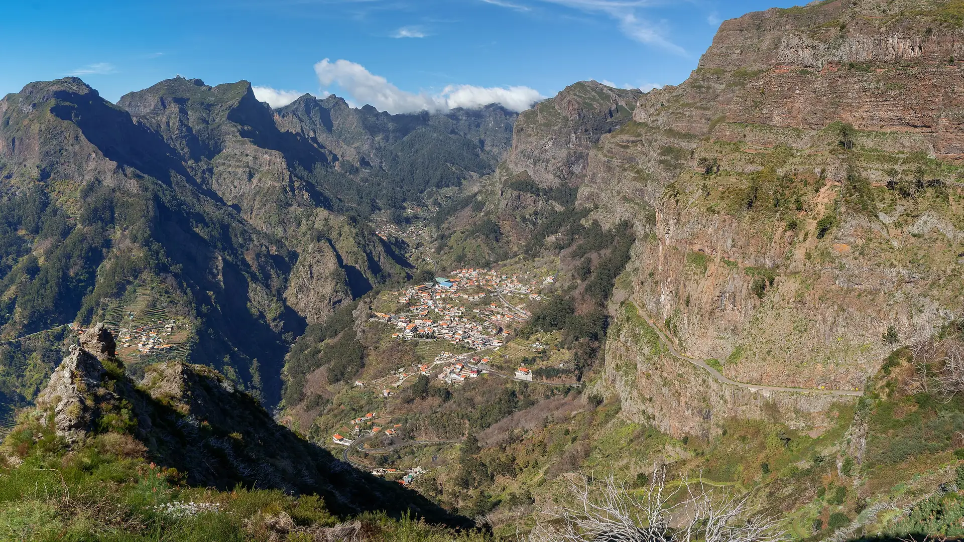 The village of Curral das Freiras on the valley floor, ringed by steep green peaks, seen from Eira do Serrado, Madeira