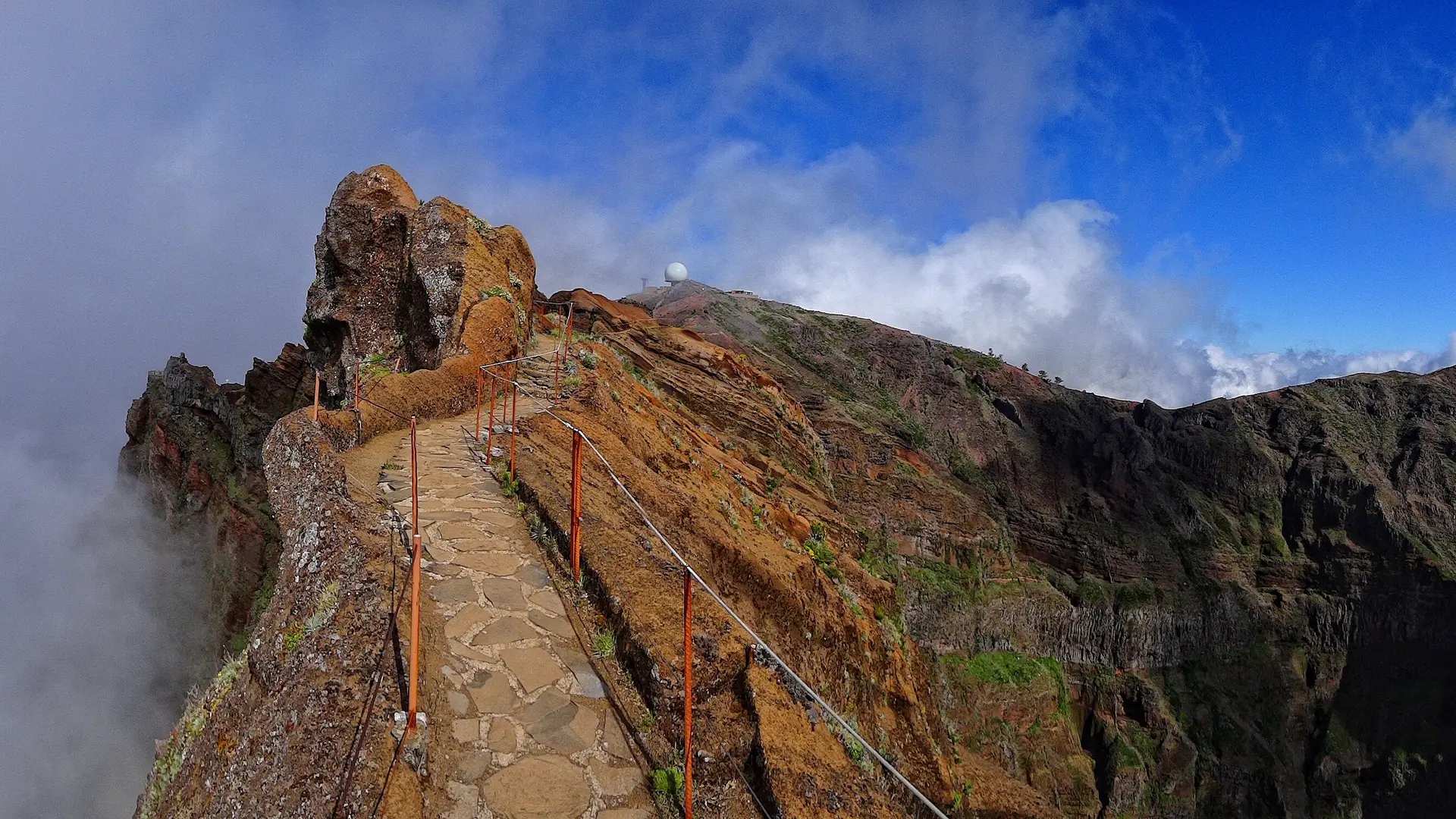The paved ridge trail at Pico do Arieiro winding between volcanic peaks above the clouds, Madeira