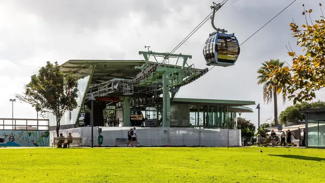 A cabin arriving at the Monte cable car station above Funchal, with families waiting on the terrace below